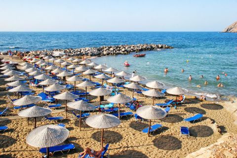 The sandy beach of Panormos with umbrellas and sun loungers