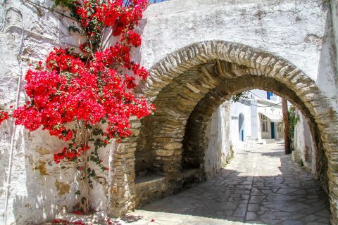 A stone built arch and fuchsia flowers on Tinos island