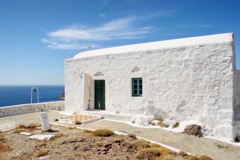 A small, whitewashed Cycladic building with green windows