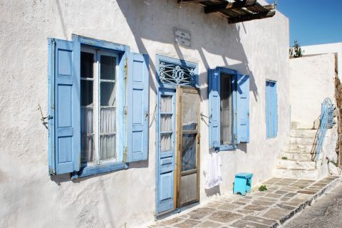 A whitewashed Cycladic building with blue-colored windows