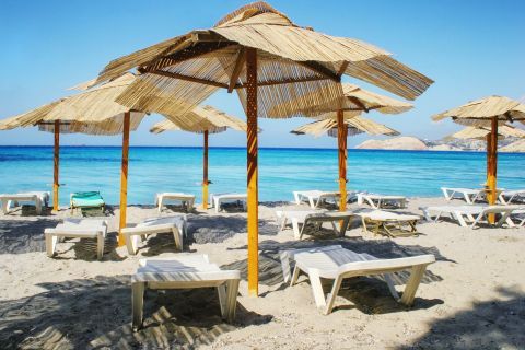 Some umbrellas and sun loungers on the beachfront of Firiplaka beach.