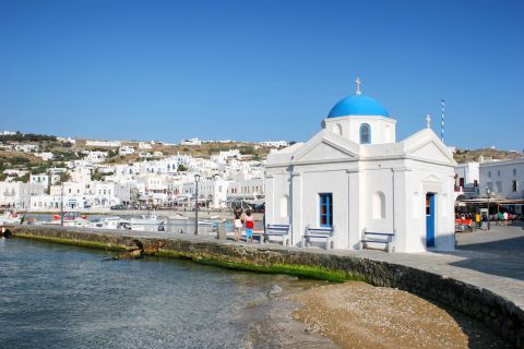 Traditional Cycladic white and blue chapel situated by the sea
