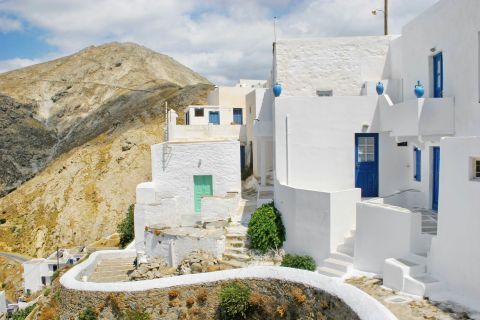 Whitewashed houses with blue or green colored details, surrounded by mountainous hills. Serifos.