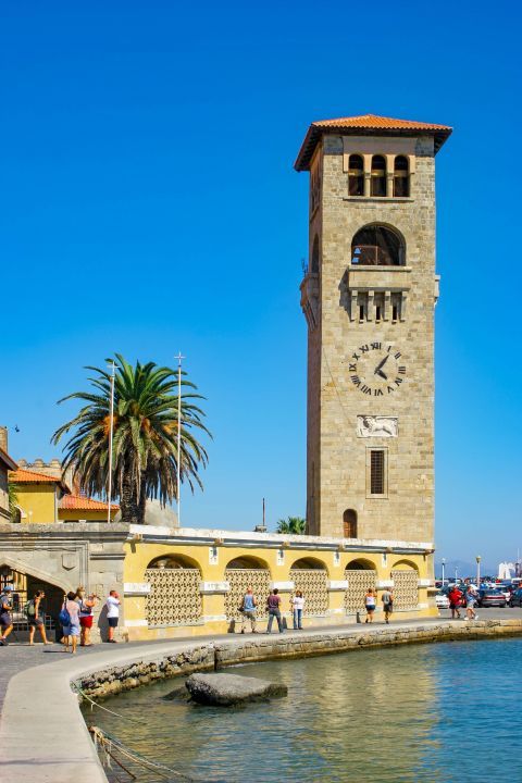 Church of Annunciation: A tall bell tower with a clock is located at the side entrance of the church, facing the harbor.