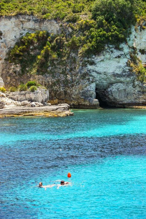 Antipaxos Island: Abrupt cliffs with green spots, surrounded by blue waters.