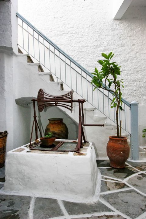Vallindras Distillery: A whitewashed yard with traditional, Cycladic flowerpots and an old well