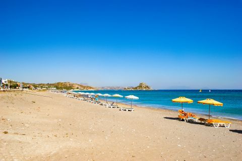 Kefalos beach: Umbrellas and sun loungers by the sea.