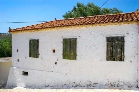 Kambi: A white colored building with wooden shutters and ceramic roof tiles.