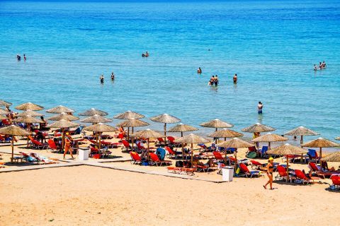Spanzia: Umbrellas and sun loungers by the sea.