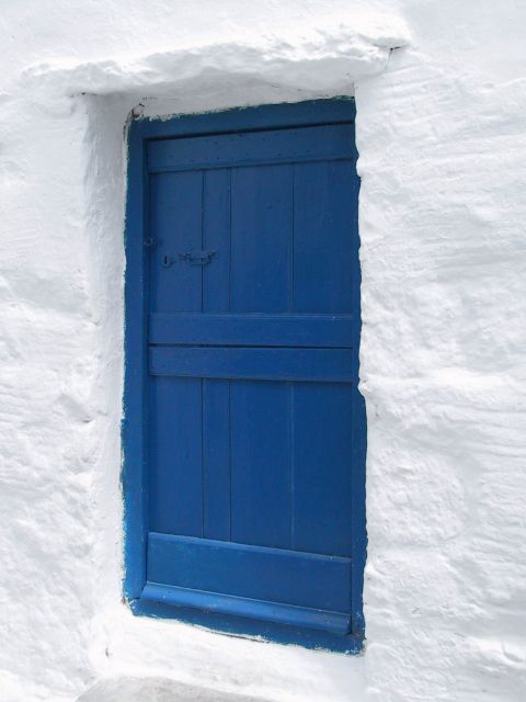 Volax: A whitewashed house with a blue dor