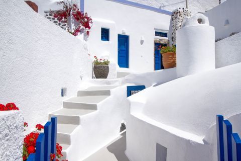 Imerovigli: A whitewashed house with blue-colored details and flowers