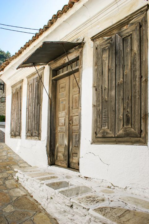 Manolates: A whitewashed house with wooden doors and shutters.