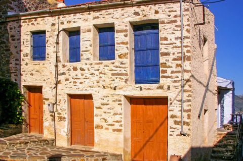 Volissos: Stone-built house with colorful, wooden shutters and doors.