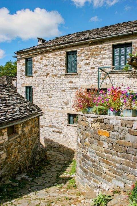 Mikro Papigo: A two-story, stone-built house with with turquoise shutters and doors