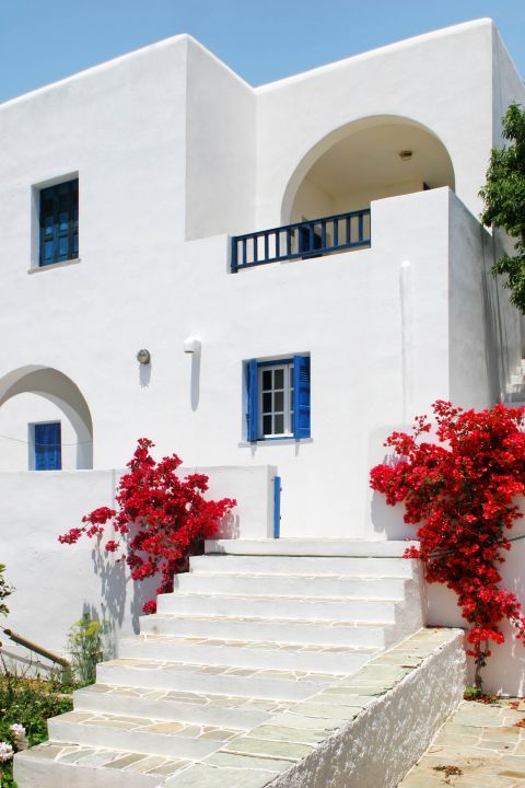 Chora: A two-story building, painted in white and blue colors, decorated with fuchsia flowers.