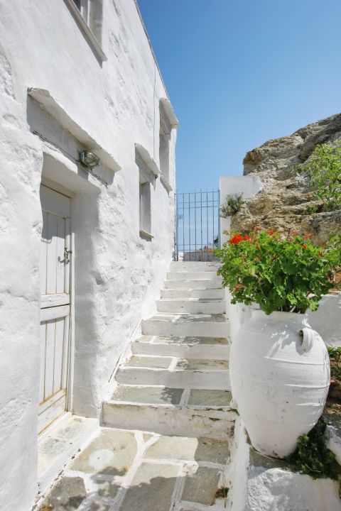 Chora: A whitewashed house and a white amphorae-like vase with lovely flowers.