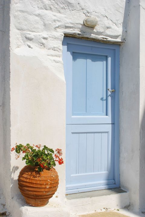 Chora: A ceramic vase with lovely flowers perfectly decorates the entrance of a traditional house.