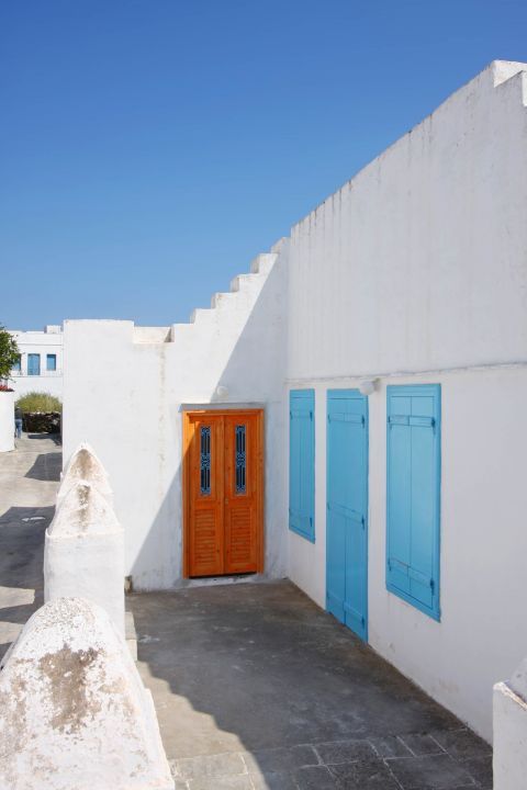 Artemonas: A whitewashed house with colorful windows and a wooden door