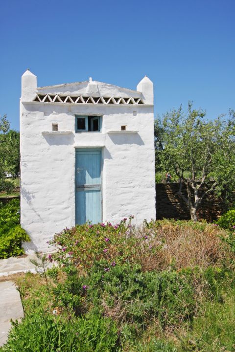 Artemonas: A whitewashed building, surrounded by lush vegetation