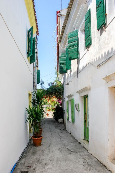 Gaios: A narrow path between two whitewashed houses with green-colored shutters.