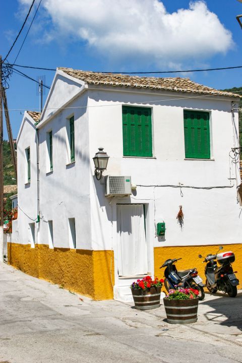 Gaios: A white-colored house with green shutters.