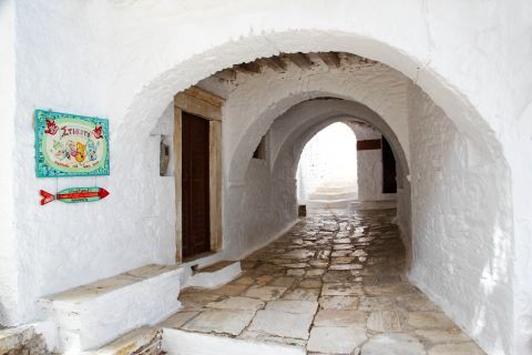 Apiranthos: A whitewashed building with wooden details and a stone paved path