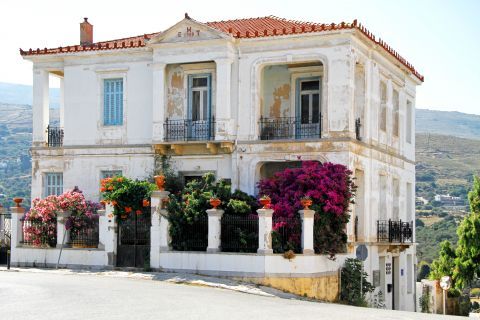 Chora: An old, two-storey mansion with lush, colorful flowers in its yard.
